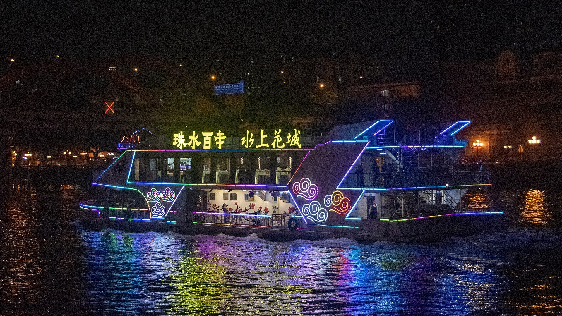 A brightly lit Pearl River sightseeing boat reflecting on the water at night in Guangzhou.