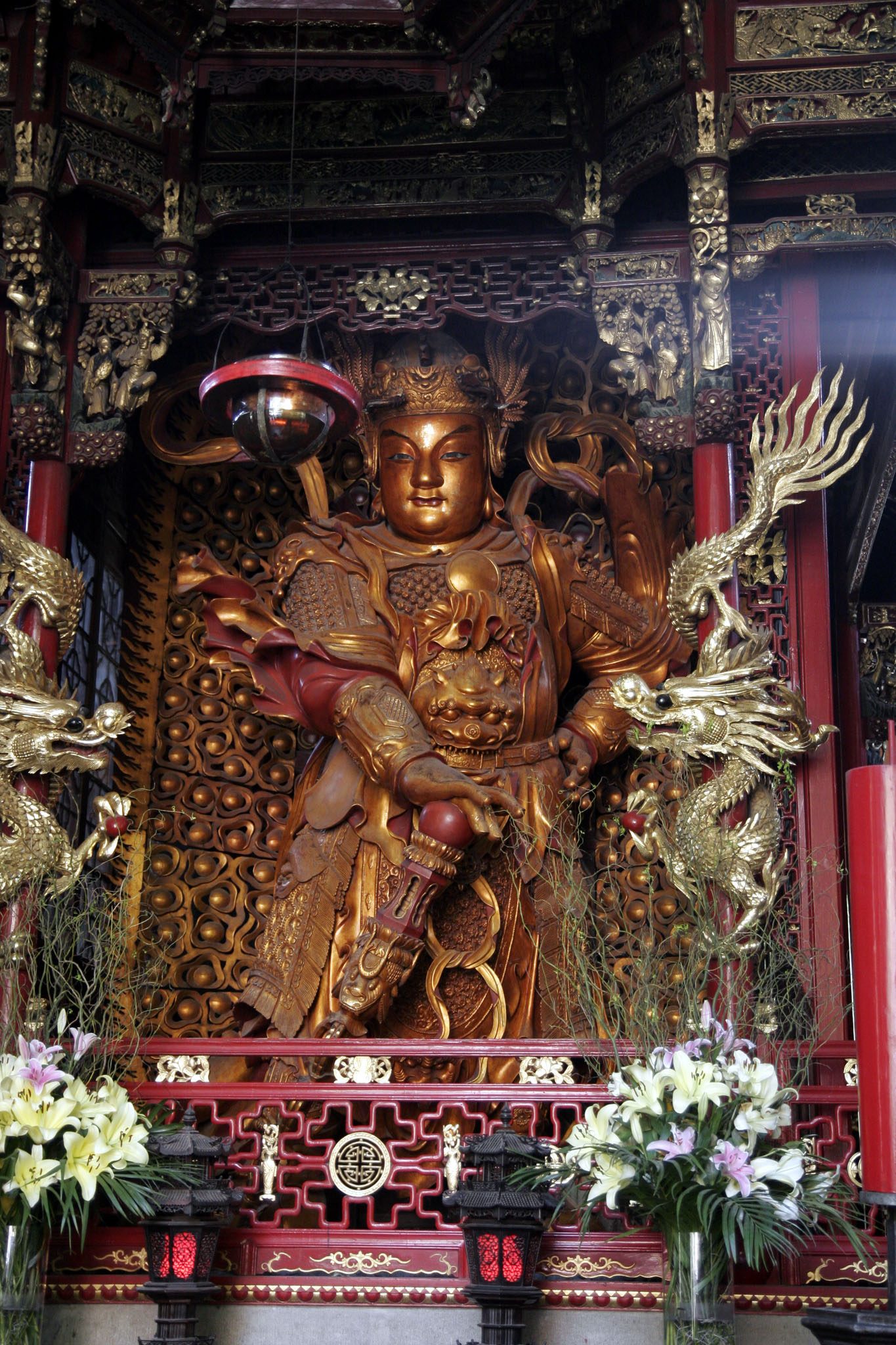 The main hall of Lingyin Temple in Hangzhou framed by tall trees and visitors in the foreground.