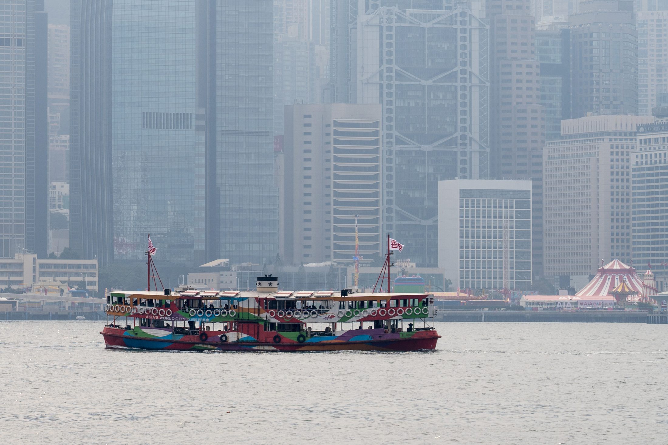 A Star Ferry crossing Victoria Harbour with Hong Kong's skyline in the background.
