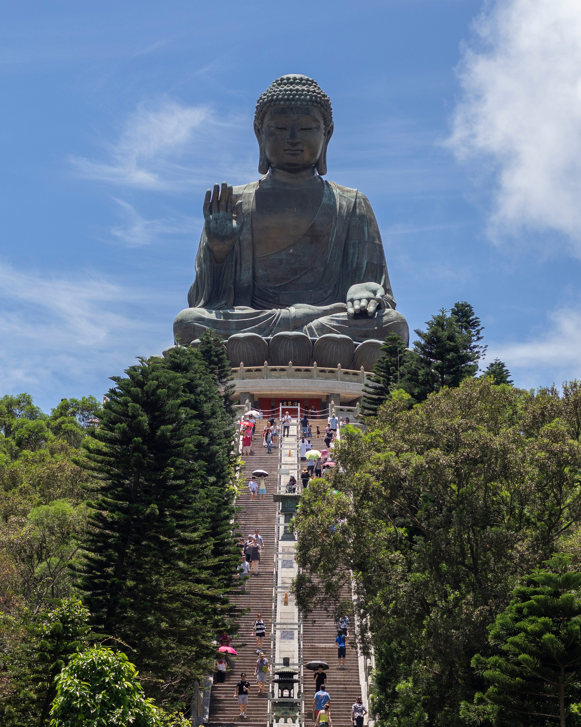 The Tian Tan Buddha above the main stairway on Lantau Island under a bright blue sky.
