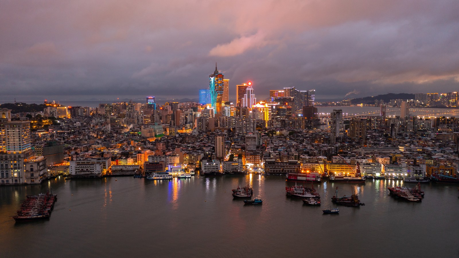 Macau Peninsula at night with Grand Lisboa and surrounding city lights seen across the waterfront.