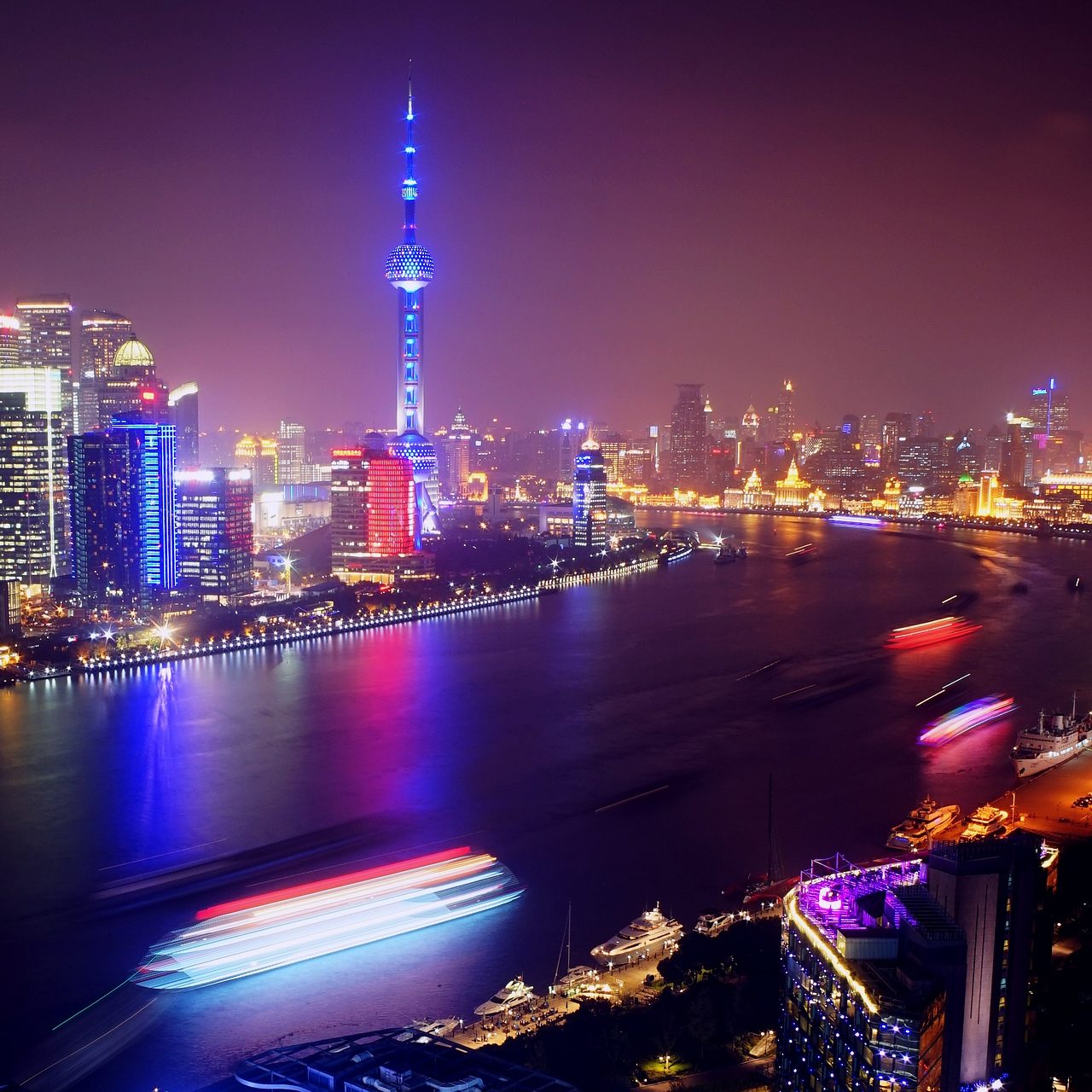 Oriental Pearl Tower glowing over the Huangpu River and the Shanghai skyline at night.