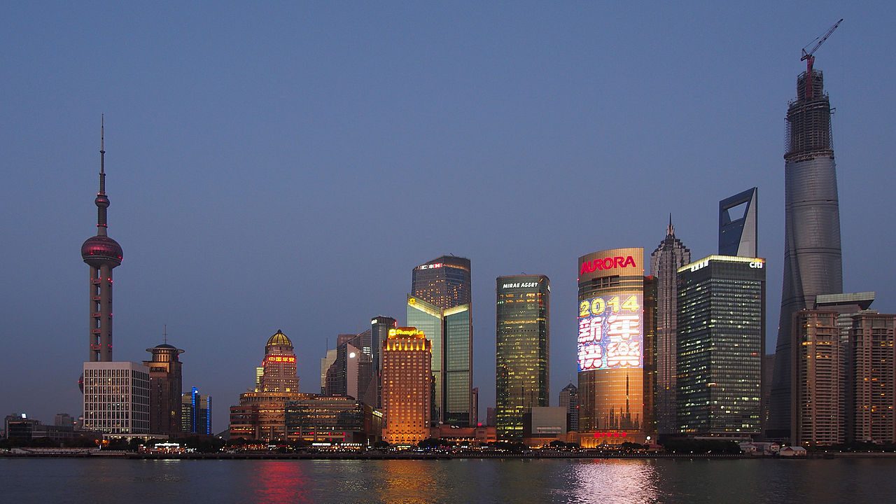Shanghai Tower rising over the Pudong skyline and Huangpu River at dusk.