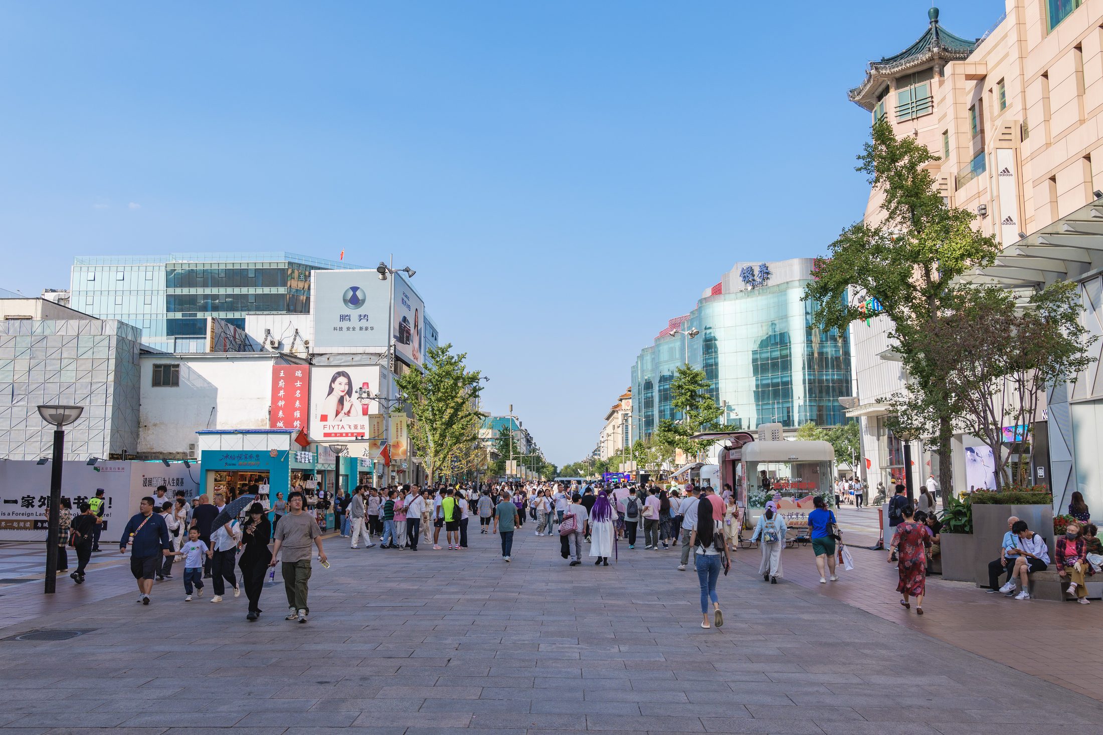 People strolling along the wide Wangfujing pedestrian street lined with modern storefronts in Beijing.