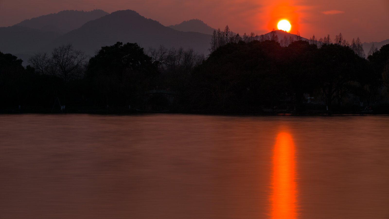West Lake in Hangzhou under soft light, where water, trees, and built form settle into one continuous surface.