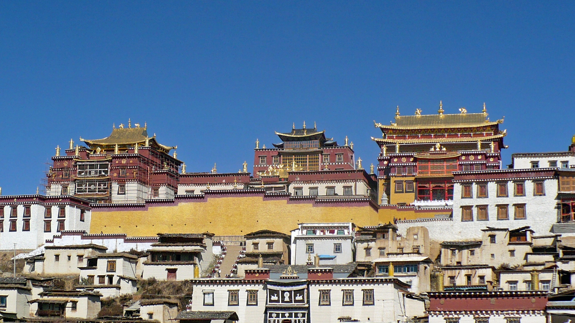 Songzanlin Monastery outside Shangri-La, where gold roofs and thick walls lift the route out of picturesque travel and into something broader, colder, and more ceremonial.