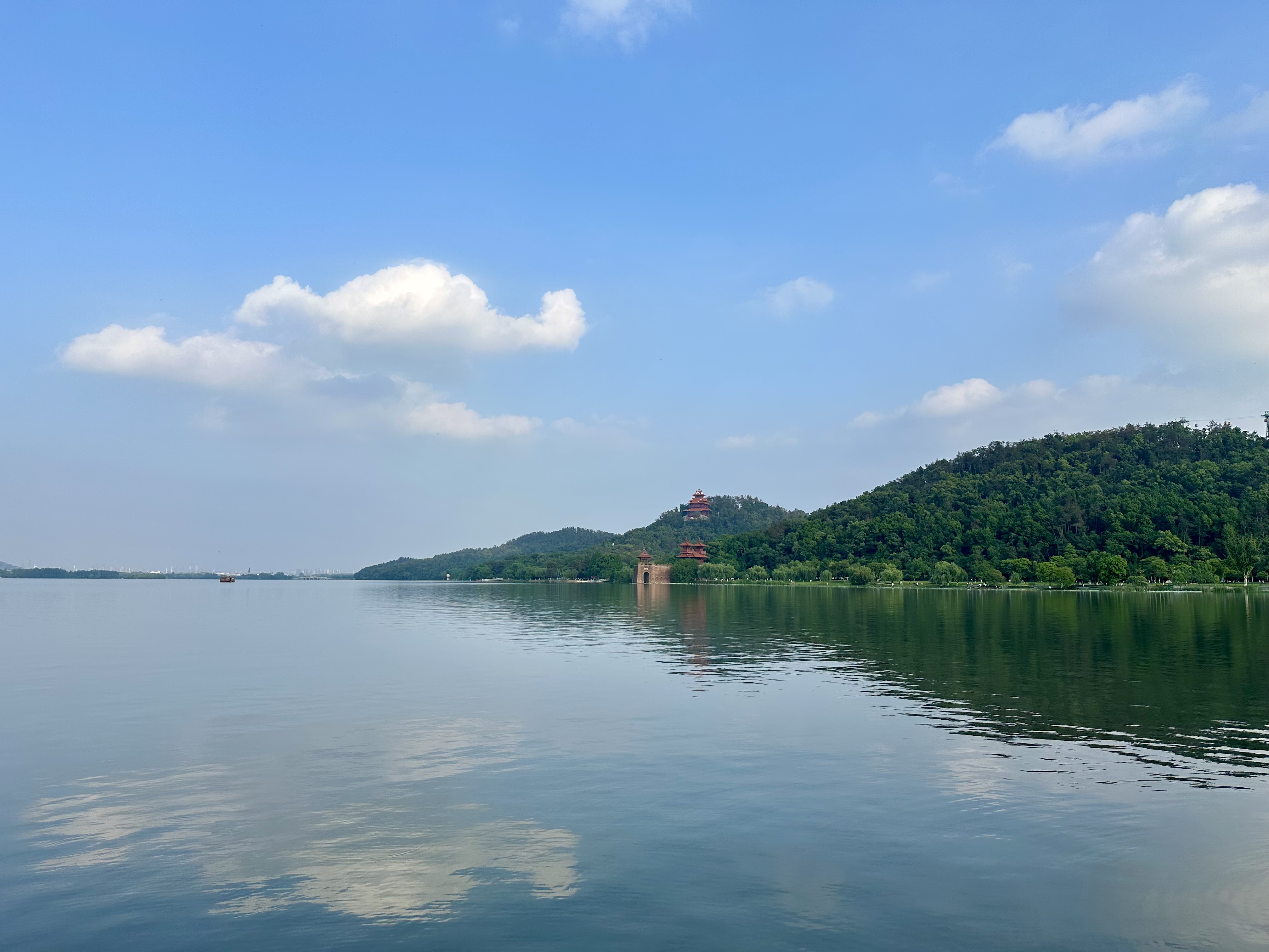 East Lake in Wuhan under a wide blue sky with tree-lined shores and layered city distance.